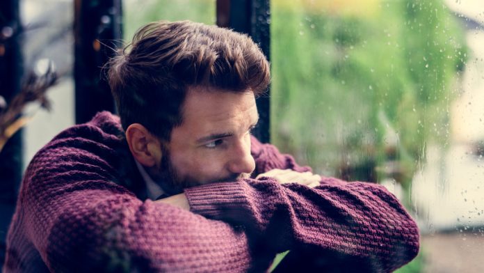 A pensive man looks out of a window