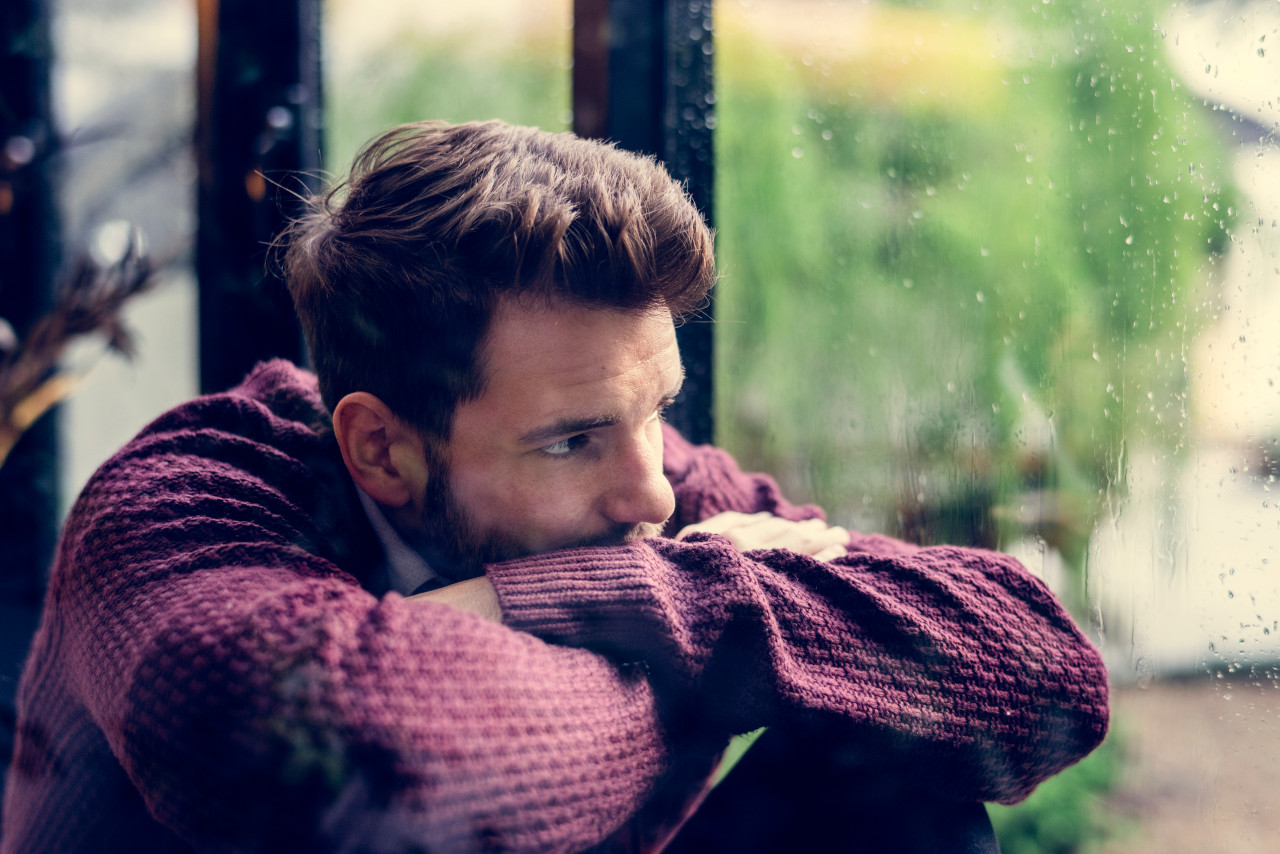 A pensive man looks out of a window