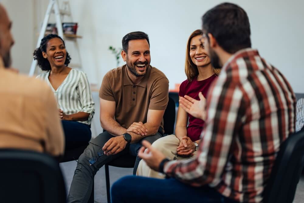 A group of people talking to each other at a support group. Learn more about NA meetings, what they are, and where you can find one, here.