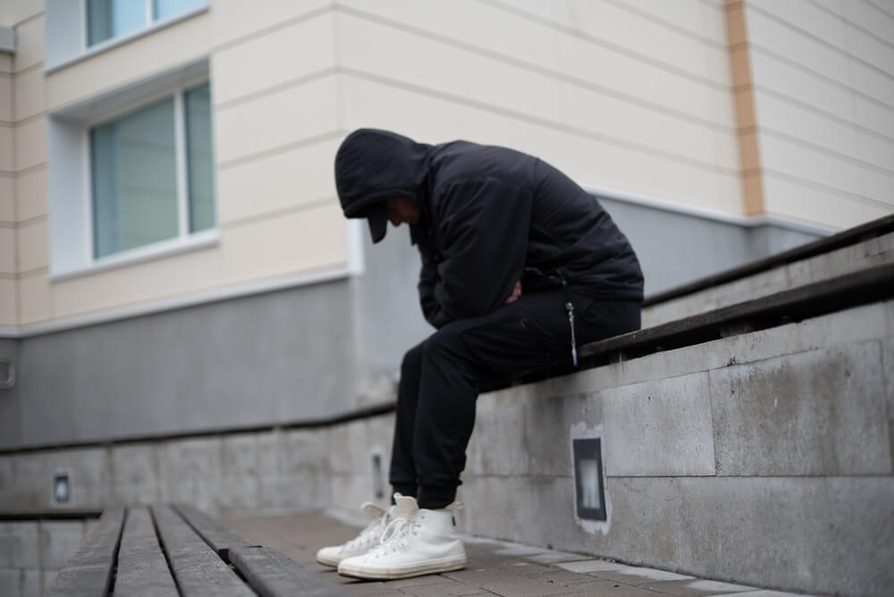 A sketchy looking man sitting on the curb. Learn more about Black Tar heroin here.