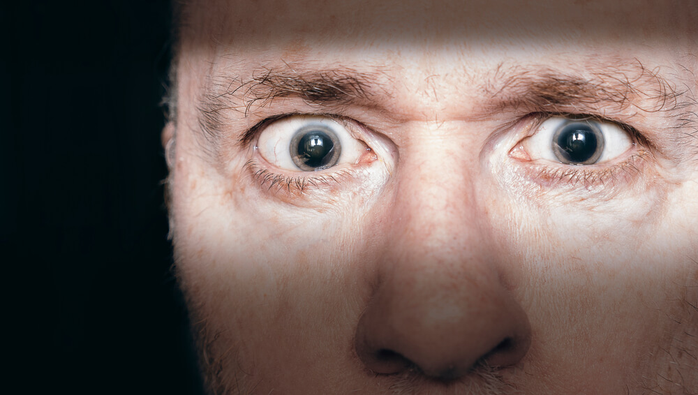 A man with dilated pupils. Learn more about hallucinogen addiction signs here