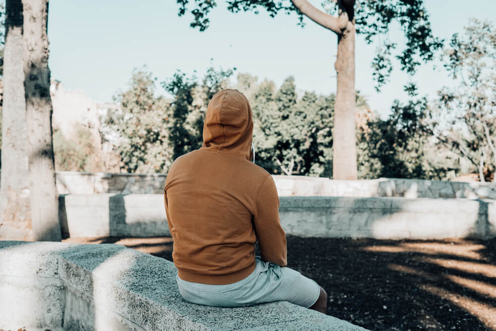 A lonely person sits on a ledge at a park. Learn more about narcotics abuse, risk factors, and treatment options here. 