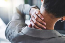 A person grips their neck as if it were sore. Learn more about non narcotic pain relief here.