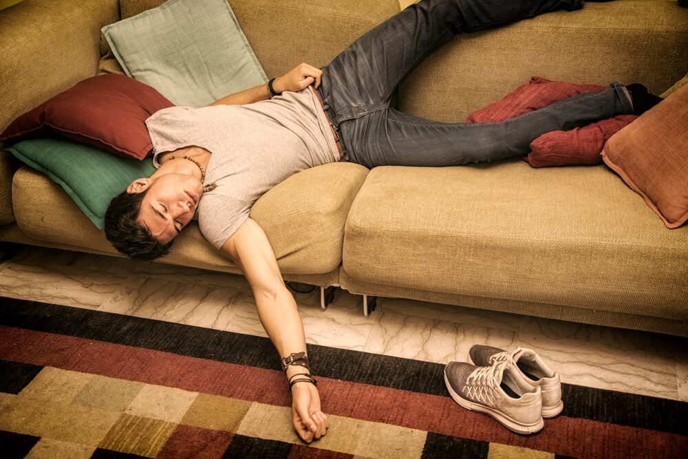 A man passed out on the couch. Learn more about the dangerous combination of opioids and alcohol here