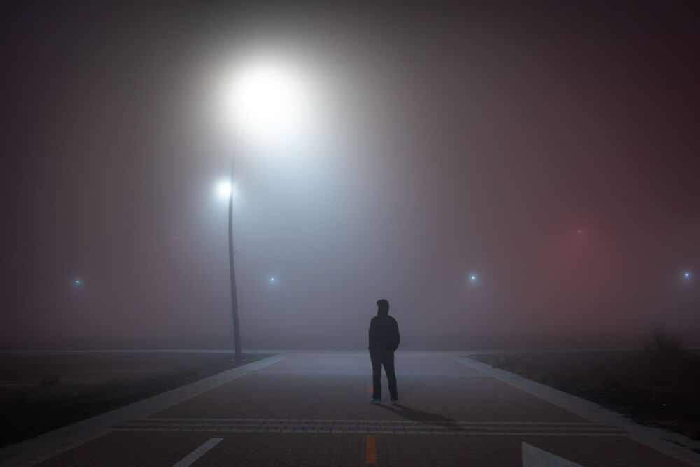 A man standing in the middle of a dark street. Learn more about oxycodone street names here.