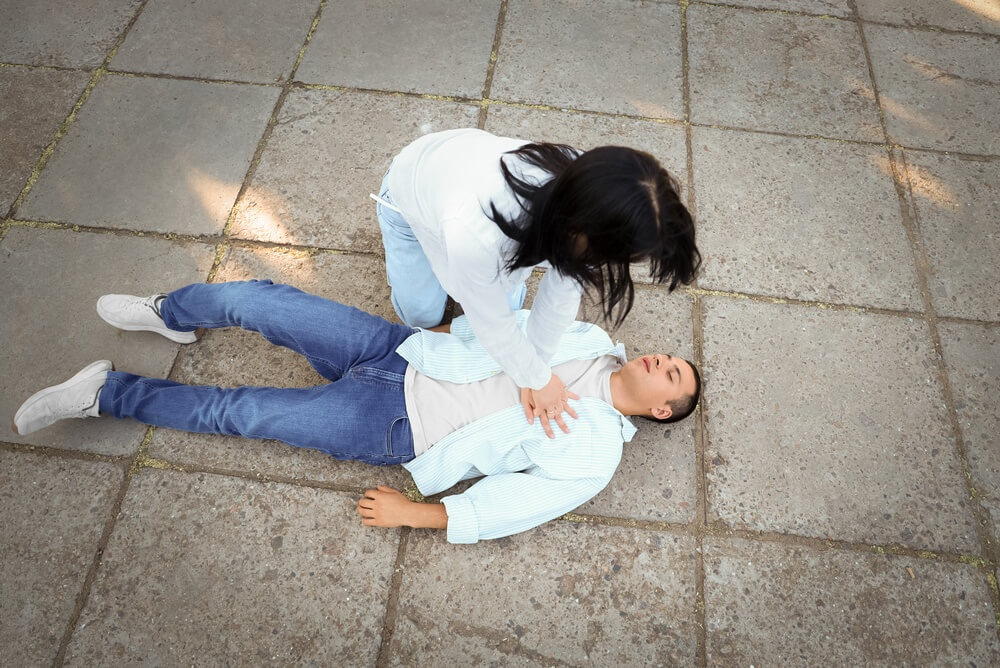 A woman performing CPR on an unconscious man. Learn more about what happens during a narcotics overdose here